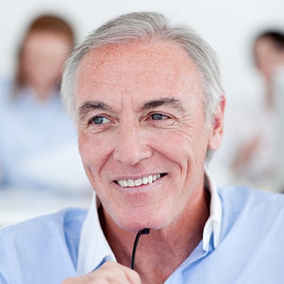 Older man holding glasses and smiling.